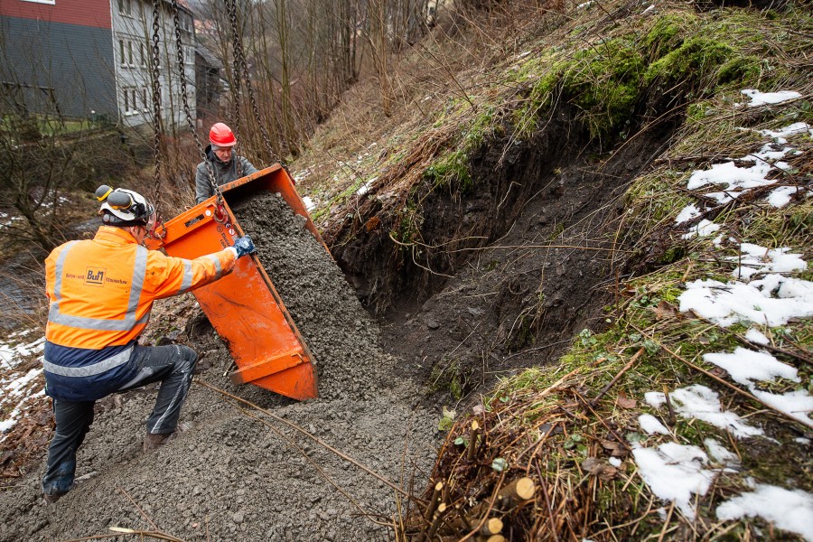 Arbeiter füllen Kies in ein Erdloch am Badstubenberg. Im Harz wird das vier Meter tiefe Loch eines Tagesbruchs mit Beton gefüllt.