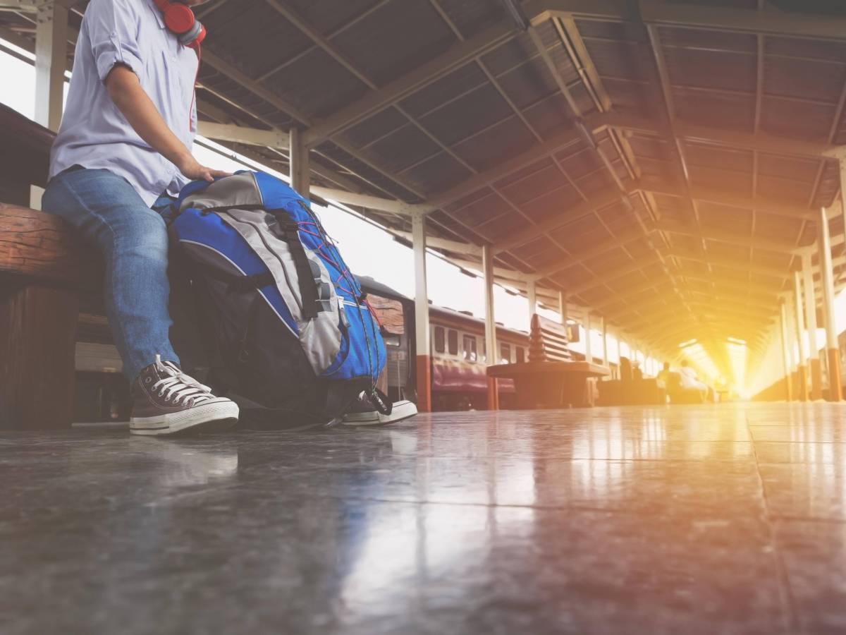 Mann mit Rucksack am Bahnhof