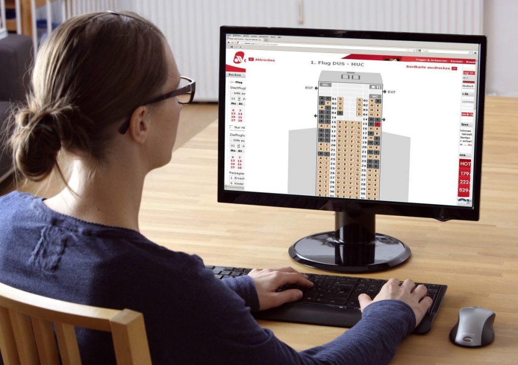Frau sitzt am Computer und bucht Flug