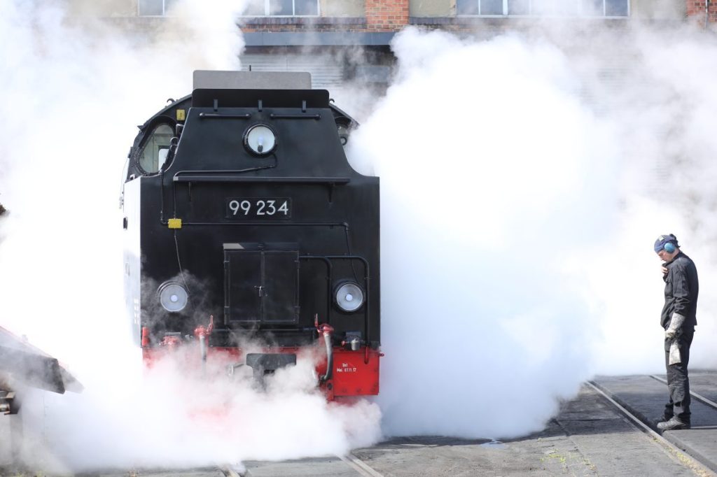 Mitarbeiter der Harzer Schmalspurbahn HSB heizen vor der Werkstatt eine Dampflokomotive an.