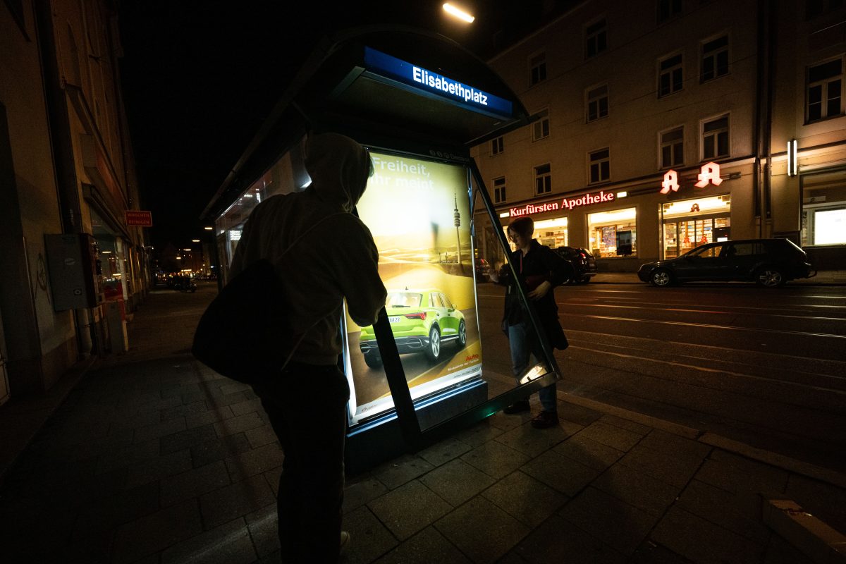 Aktivisten der Nichtregierungsorganisation Attac bringen als Protest gegen die aktuell in München laufende Messe IAA Mobility kritische Persiflagen von Autowerbung an einem Trambahnhäuschen an.