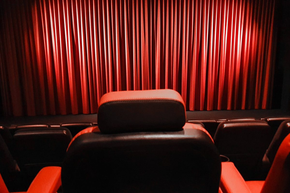 Ein leerer Kinosaal mit roten Sitzen und geschlossenen Vorhängen auf der Bühne im Kino (Symbolbild für das Astor Braunschweig)