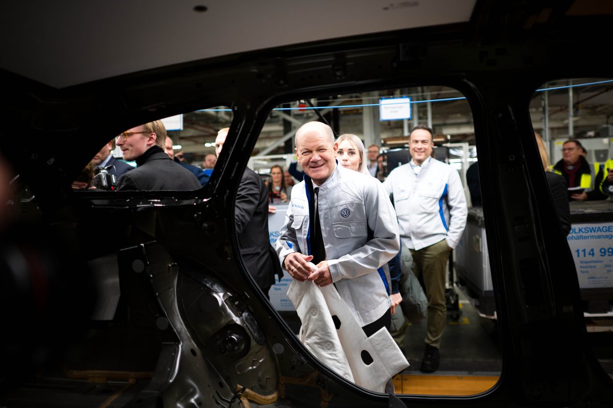 Bundeskanzler Olaf Scholz (SPD) legt im VW-Werk Emden eine Dämmmatte in einen Wagen.