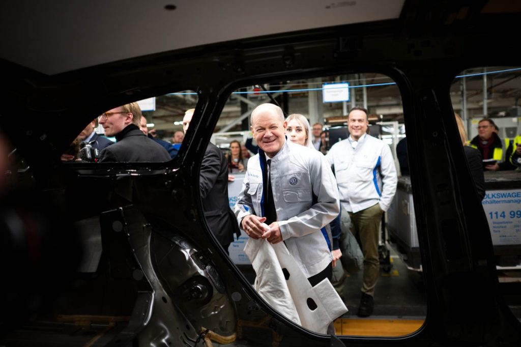 Bundeskanzler Olaf Scholz (SPD) legt im VW-Werk Emden eine Dämmmatte in einen Wagen.