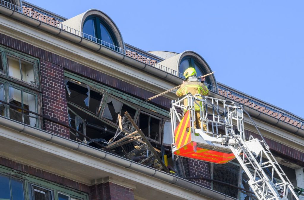 Feuerwehrkräfte sichern von einer Drehleiter aus eine zerstörte Fassade an einem Gebäude von Continental.